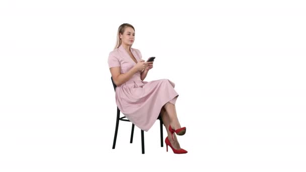 Στοχαστικός γυναίκα σε ροζ φόρεμα γραπτών μηνυμάτων για το έξυπνο τηλέφωνο σε λευκό φόντο. — Αρχείο Βίντεο