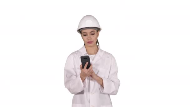 Kadın mühendis beyaz arka planda yürürken telefonda konuşuyor.. — Stok video