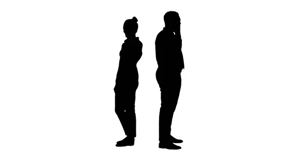 Силуэт Молодой афроамериканец мужчина и женщина стоят спиной к спине и делают телефонные звонки. — стоковое фото