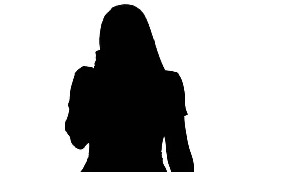 Silhouette giovane donna parlando con qualcuno sul suo telefono cellulare . — Foto Stock