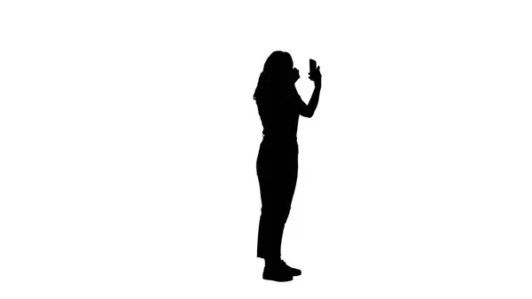 Silhouette Hübsche junge Frau, die Mascara aufträgt und auf ihr Handy schaut. — Stockfoto