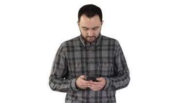 Genç adam yürüyor ve beyaz arka planda akıllı telefon kullanıyor..