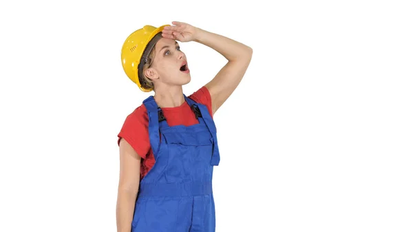 Ingeniera mujer trabajadora de la construcción mirando hacia arriba sorprendida sobre fondo blanco . — Foto de Stock