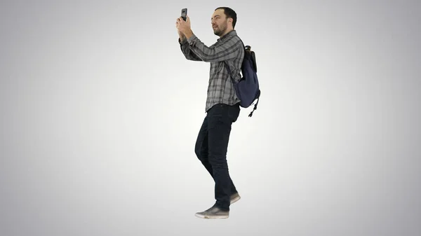 Giovane studente attraente zaino in spalla turistico scattare foto selfie con telefono cellulare su sfondo gradiente . — Foto Stock