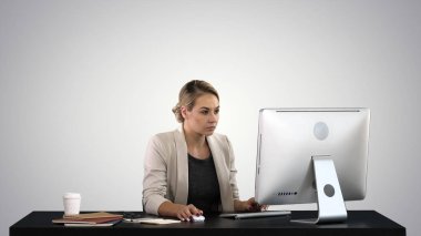 Beautiful blonde woman working on computer on gradient background. clipart