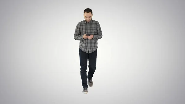 Молодой человек ходит и пользуется телефоном, обмениваясь сообщениями на градиентном фоне . — стоковое фото