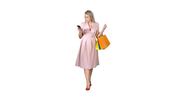 Shopping femme avec sacs SMS message sur smartphone tout en marchant sur fond blanc . — Photo