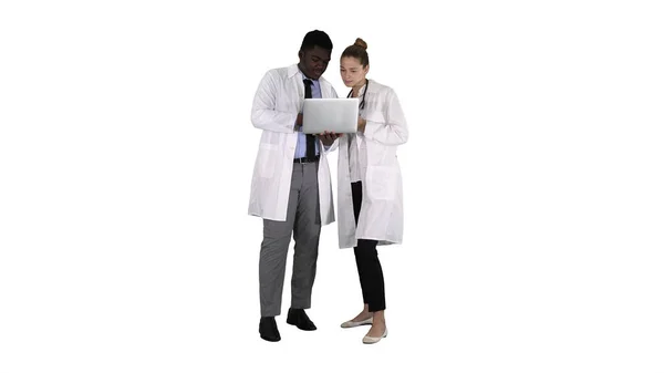 Equipe médica trabalhando na frente de um laptop cinza enquanto está em pé sobre fundo branco . — Fotografia de Stock