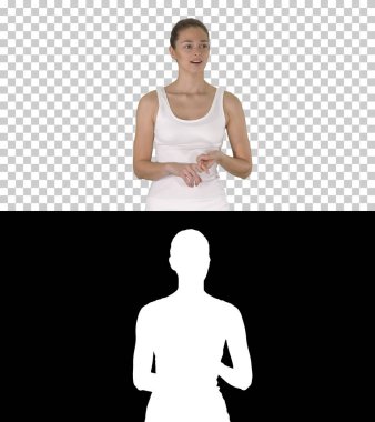 Beyaz bluzlu güzel bir kadın, Alpha Channel 'da yürüyor ve kamerayla konuşuyor.