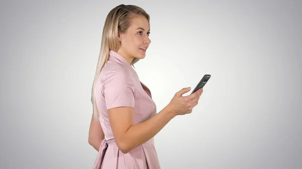 Mulher feliz selecionando conteúdo on-line em um telefone inteligente no fundo gradiente . — Fotografia de Stock