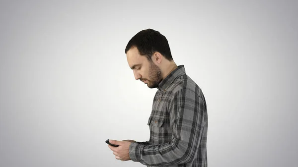 Joven hombre de negocios casual inteligente leyendo el mensaje en el teléfono celular en el fondo de gradiente. — Foto de Stock