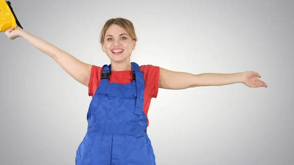 Female construction worker dancing with hardhat on gradient background.