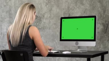 Hippi kız moda gözlük bilgisayar çalışma önünde masada oturur. Yeşil perde Mock-up göstermek.