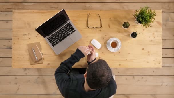 Młody biznesmen przyjmuje lek siedząc w pracy przed laptop. — Wideo stockowe