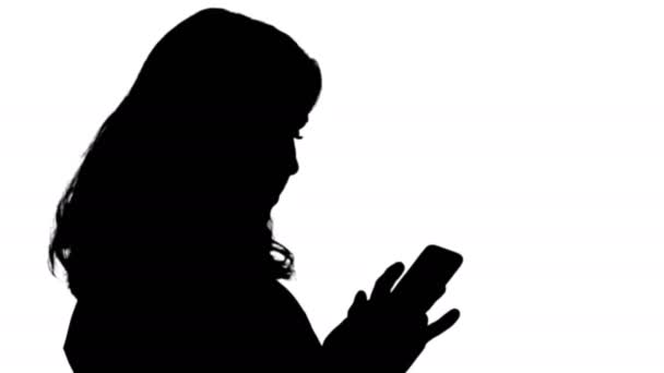 Силуэт Счастливая женщина просматривает медиа или смс на мобильном смартфоне . — стоковое видео