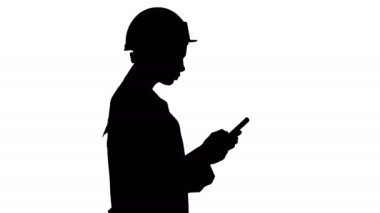 Siluet Mühendisi yürürken cep telefonu mesajı kullanıyor.