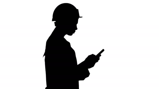 Silhouette Engineer usando mensajes de texto de teléfonos móviles mientras camina. — Vídeos de Stock