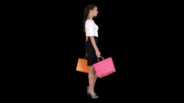 Jeune femme avec des sacs à provisions marchant hors du magasin, Alpha Channel — Video