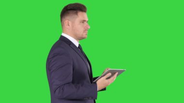 Genç işadamı dokunmadan dijital tablet ve kontrol nesne onun önünde yeşil ekran, Chroma anahtar.