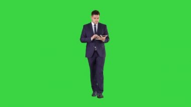 Takım elbise yürüyüş ve yeşil ekran üzerinde dijital tablet kullanarak adam, Chroma anahtar.