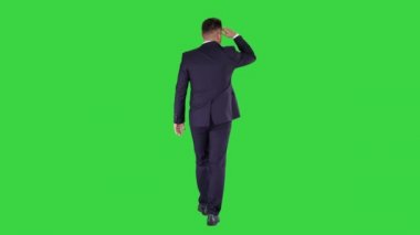 İş adamı yürüyüş ve uzak bir yeşil ekran üzerinde seyir, Chroma anahtar.