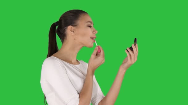 Όμορφη νεαρή γυναίκα βάζοντας το κραγιόν σε μια πράσινη οθόνη, πλήκτρο αποχρώσεων. — Αρχείο Βίντεο