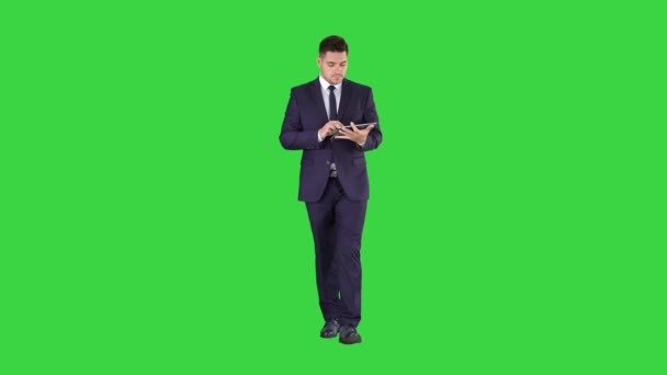 Άντρας σε φόρμα που περπατάει και χρησιμοποιεί ψηφιακό tablet σε πράσινη οθόνη, πλήκτρο αποχρώσεων. — Αρχείο Βίντεο