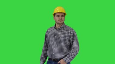 Sarı kaskında gülen inşaat işçisi mükemmel iyi inşa nesne eller yeşil ekran üzerinde kalça üzerinde, chroma key bakıyor.