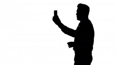 Siluet Mutlu genç yakışıklı iş adamı video kaydı yapıyor veya video çağrısı yapıyor.