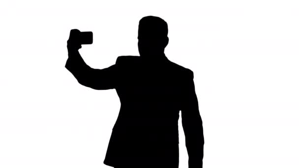 Silhouette bel homme en costume prendre un selfie tout en marchant . — Video