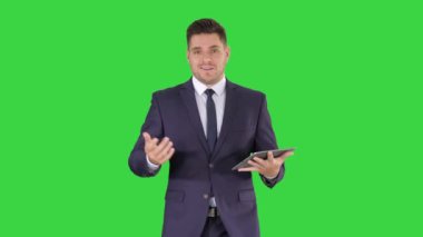 İşadamı tabletüzerinde sayfaları kaydırma ve yeşil ekranda yürürken bir şey açıklayan kamera konuşuyor, Chroma Anahtar.