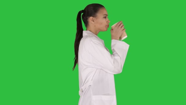 Female doctor drinking coffee and walking on a Green Screen, Chroma Key. — Stock Video