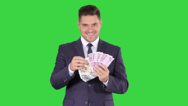 Człowiek biznesu pokazujący banknoty euro uśmiechnięty na zielonym ekranie, Klucz chrominancji. — Wideo stockowe