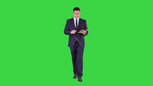 Uomo d'affari a piedi e pagine strisciando sul suo computer tablet e cercando di fotocamera che presenta qualcosa su uno schermo verde, Chroma Key . — Video Stock