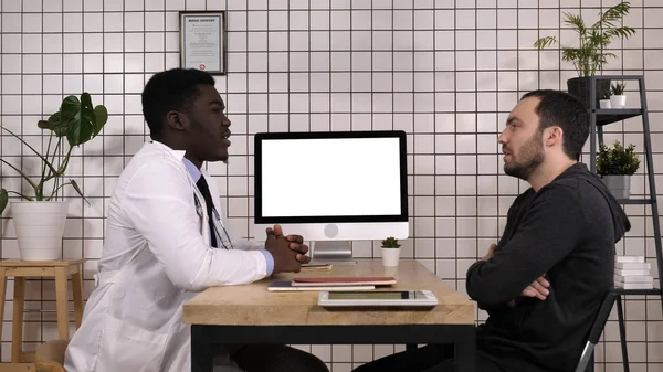 Ο γιατρός μιλάει στον άντρα ασθενή του. Λευκή οθόνη. — Φωτογραφία Αρχείου