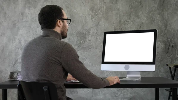 Un giovane uomo d'affari barbuto che si agita al computer. Display bianco. — Foto Stock