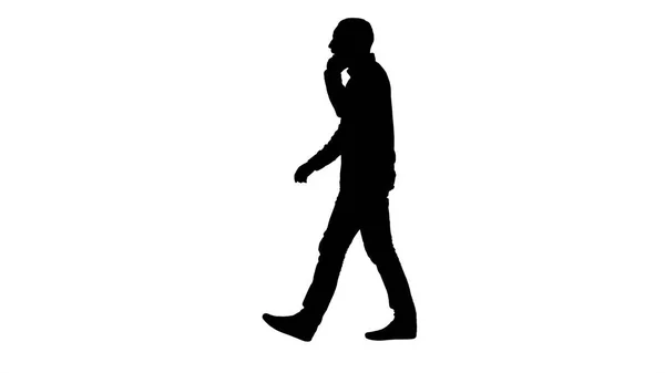 Silueta Mladý vousatý muž chodí a mluví na mobilním telefonu. — Stock fotografie
