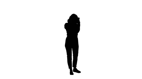 Mooie jonge vrouw met behulp van mascara en op zoek in haar smartphone silhouet. — Stockfoto