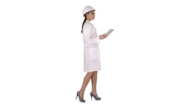 Beyaz arka plan üzerinde nesnelerin çevresine bakarak tablet ile yürüyen genç bir kadın mühendis.