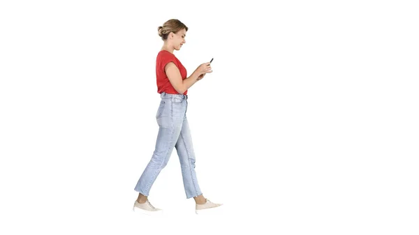 Mooie jonge vrouw wandelen en het lezen van sms-bericht op haar mobiele telefoon op witte achtergrond. — Stockfoto