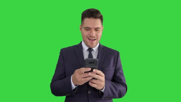 Бізнесмен дивиться на смартфон з сюрпризом вираз на зеленому екрані, ключ кольоровості. — стокове відео