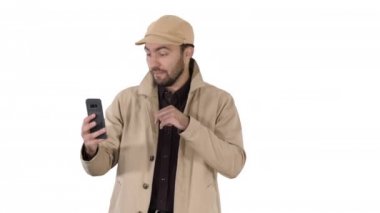 Genç adam beyaz arka planda yürürken cep telefonundan bir video görüşmesi yapıyor..