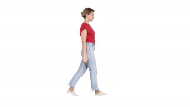 Woman in red t-shirt, jeans and sneakers walking on white background. — Stock Video