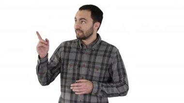 Yakışıklı genç adam yürüyüş ve kameraya bakarak ve beyaz arka plan üzerinde bir şey gösteren yanları işaret.