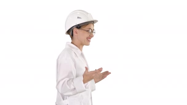 Científico joven en bata de laboratorio y hardhat caminando y diciendo algo sobre fondo blanco . — Vídeos de Stock