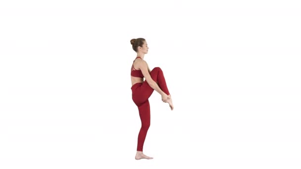 Mujer yogui joven practicando el concepto de yoga, Variación de Utthita Hasta Padangushthasana pose, Trivikramasana, de pie se divide en fondo blanco . — Vídeo de stock