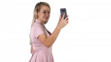 Genç güzel kadın beyaz arka plan üzerinde telefonunda selfie yapar.