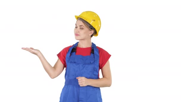 Jeune ouvrière constructeur femme présentant montrant le produit avec ses mains de ses côtés sur fond blanc . — Video