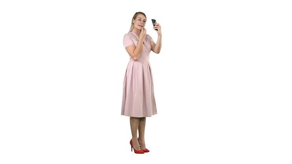 Vrouw toepassen van lippenstift kijken naar haar telefoon op een witte achtergrond. — Stockfoto