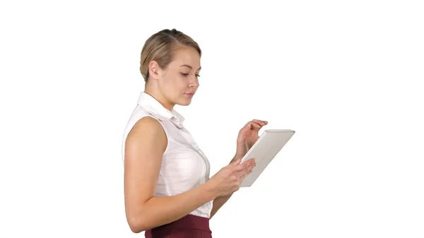 Mujer de negocios moderna usando tableta mientras camina sobre fondo blanco . — Foto de Stock